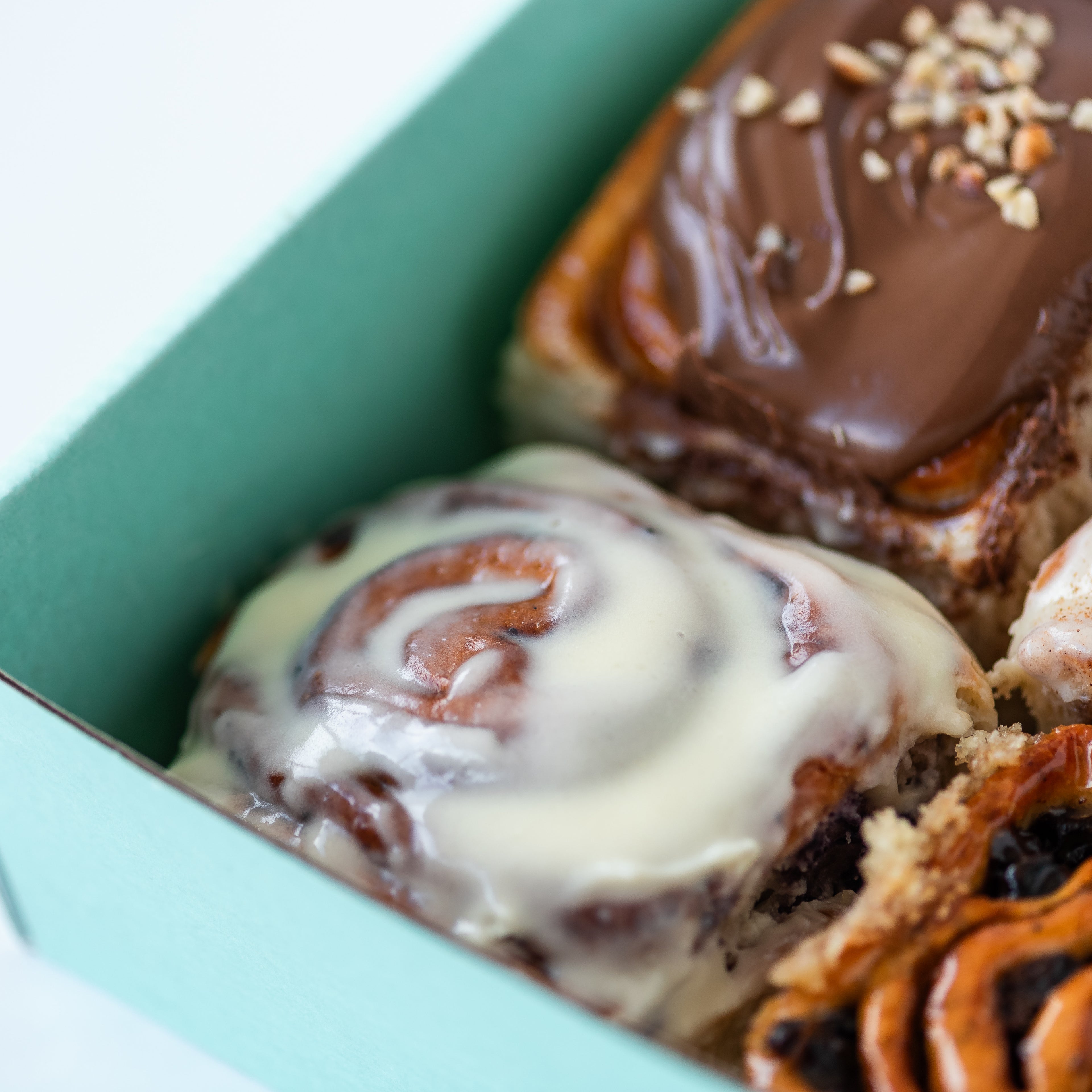 Tray of mixed iced buns in a turquoise Fitzbillies box
