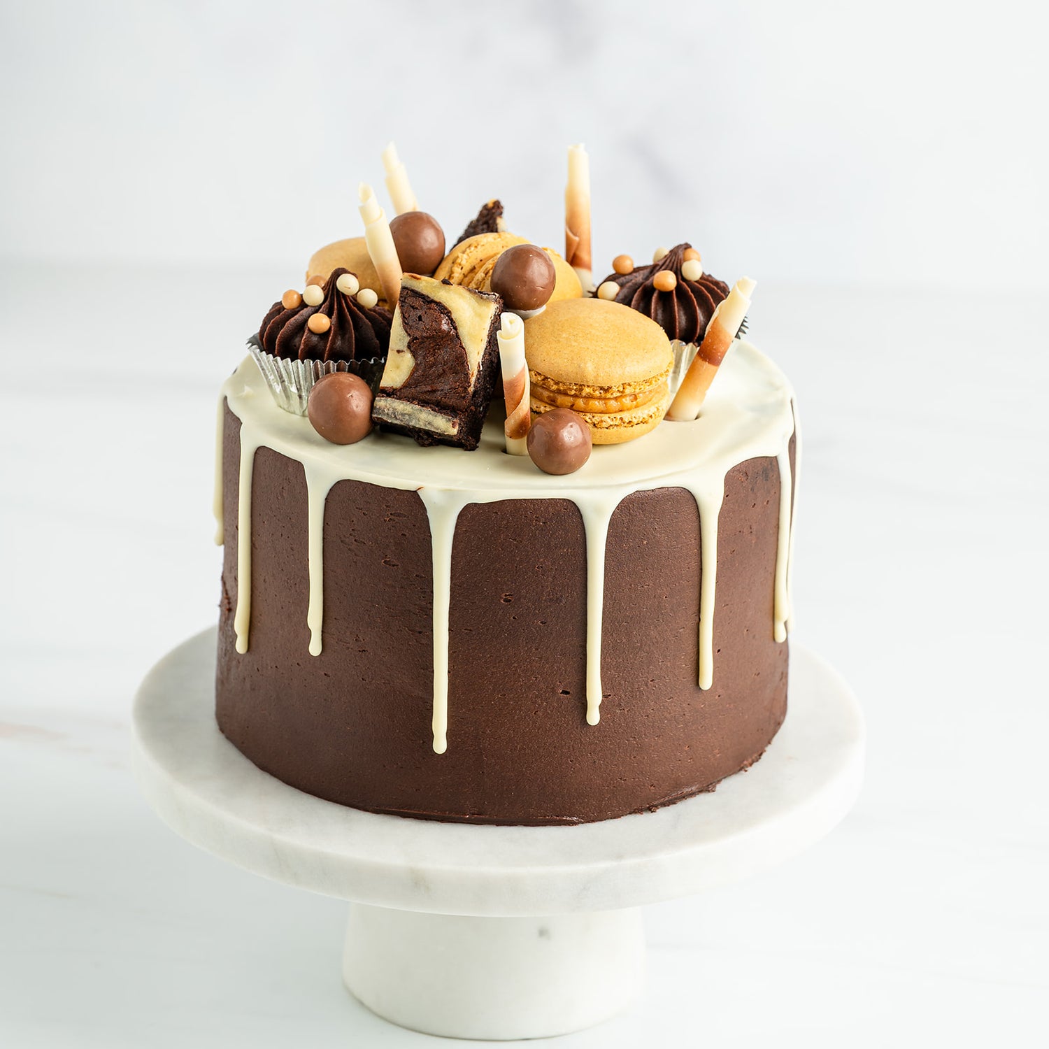 Chocolate cake with white chocolate drizzle and assorted decorations on a white background